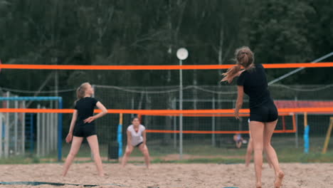 Four-girls-volleyball-players-play-on-the-beach-in-the-summer-participating-in-the-tournament-in-slow-motion-on-the-sand